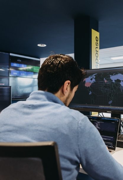 Medewerker aan een werkplek met meerdere monitoringschermen.